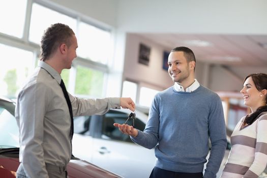 Salesman giving car keys to a smiling couple