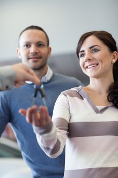 Couple receiving keys from a car dealer in a car shop