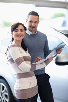 Smiling couple holding a document in a carshop