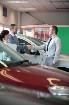 Man shaking the hand of a salesman in a car shop