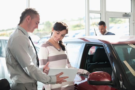 Smiling woman chatting with a car dealer in a car shop