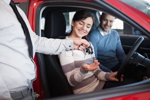 Salesman giving keys to a smiling couple in a car