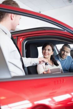 Smiling customer receiving car keys from a salesman