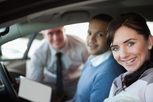 Smiling couple in a new car with a salesman