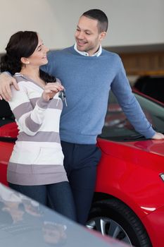 Couple standing next to a car while holding keys