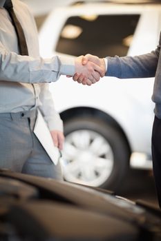 Two men shaking hand in  car shop