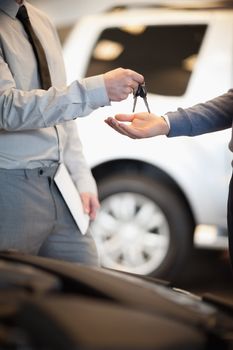 Salesman handing keys to a customer in a car shop