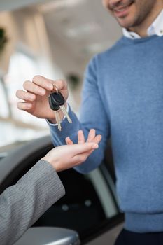 Smiling man holding keys in a car shop