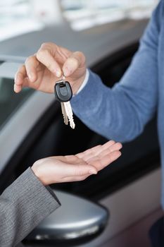 Man giving keys to a woman in a car shop