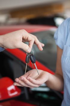 Car keys hold by someone over someone else hand in a car shop