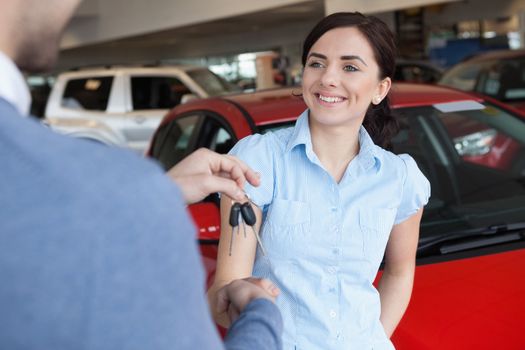 Woman smiles as she shakes someone hand in a car shop