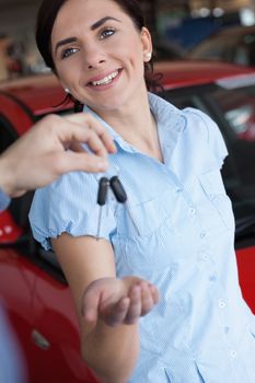 Woman smiles while receiving a car key in a car shop