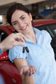 Woman smiling and receiving car keys in a car shop