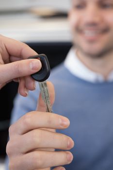 man holding a car key in a car shop