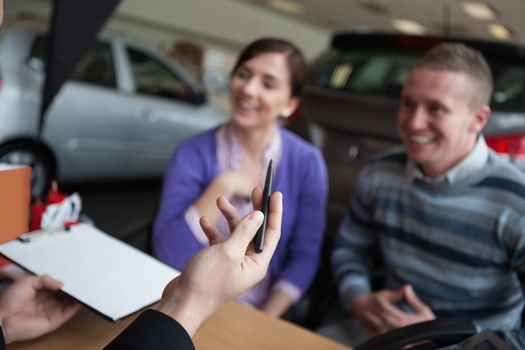 Couple listening to a car dealer in a car shop