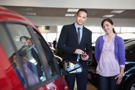Woman and a salesman standing side by side in a car shop