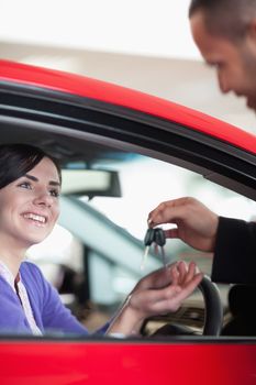 Woman smiling while receiving car keys in a car shop