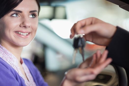 Woman smiles as she takes car keys while sitting in a car