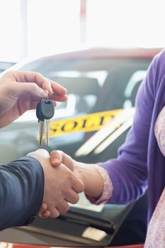 Woman shaking the hand of a man in a car dealership