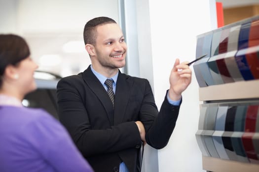 Smiling salesman pointing at a color palette with a woman