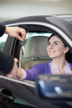 Woman smiling in a car while shaking hand and receiving car keys