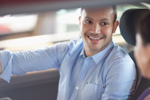 Man smiling while sitting in a car with a woman
