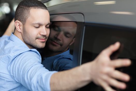 Man hugging on a car in a car dealership 