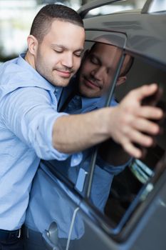 Man hugging a car in a car delaership