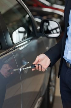 Man opening a car with a key in a car dealership