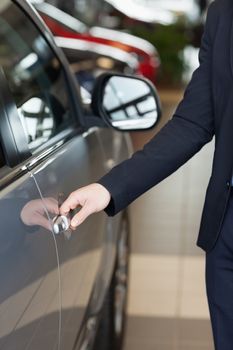 Man holding a car door handles in a car dealership