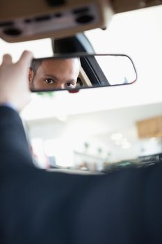 Man adjusting a rear view mirror while sitting in a car