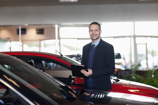 Man writing on a notepad beside a car in a garage