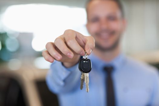 Man holding car keys by his fingertips in a dealership