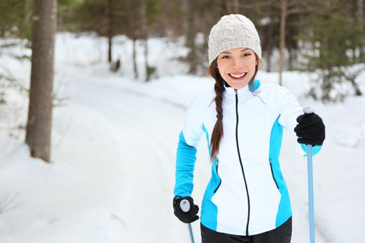 Cross-country skiing woman doing classic nordic cross country skiing in trail tracks in snow covered forest in Quebec, Canada