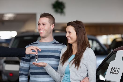 Salesman giving car keys to a woman in a dealership