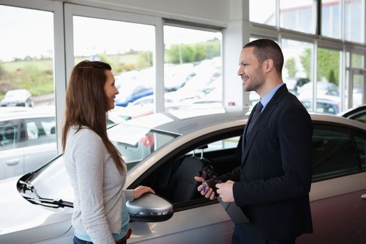 Dealer speaking to a client next to a car