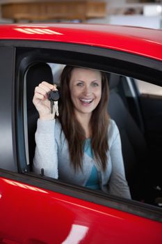 Woman holding car keys in his new car