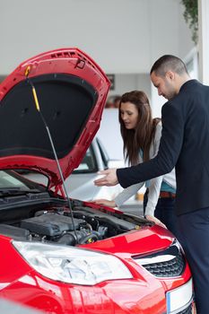 Salesman showing the car engine in a garage