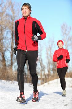 Sport in winter - People running in snow. Man and woman fitness couple.