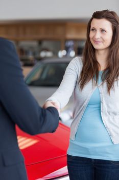 Woman shaking hand to a dealer in a garage