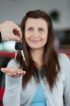 Happy brunette receiving car keys in a garage