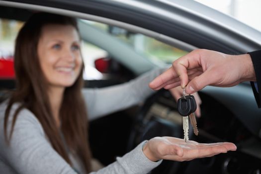 Happy woman receiving car keys in a garage