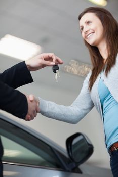 Woman receiving car keys while shaking hand in a garage