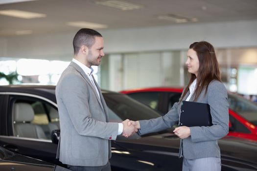Businesswoman shaking hand of a man in a dealership