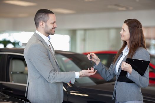 Woman giving car keys to a client in a dealership