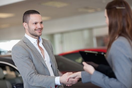 Businesswoman shaking hand of a client in a dealership