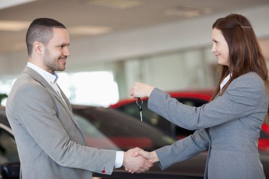 Man receiving car keys while shaking hand in a dealership