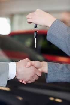Close up of a woman giving car keys to a man in a dealership