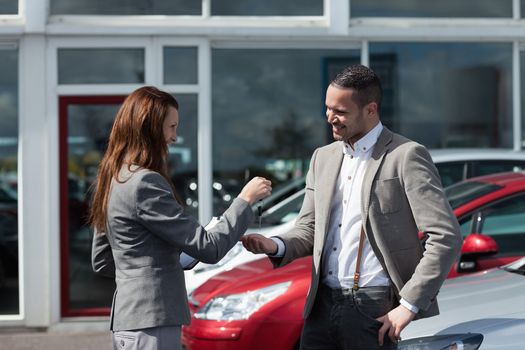 Businesswoman giving car keys to a man in a garage