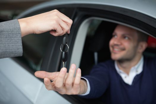 Man receiving car keys while sitting in his car in a garage